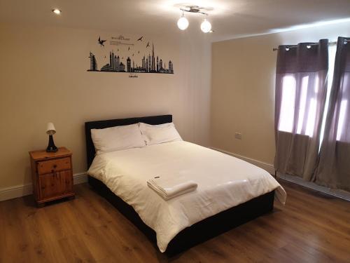 a bedroom with a bed with white sheets and a window at Two beautiful double bedroom Tulip apartment in Dagenham