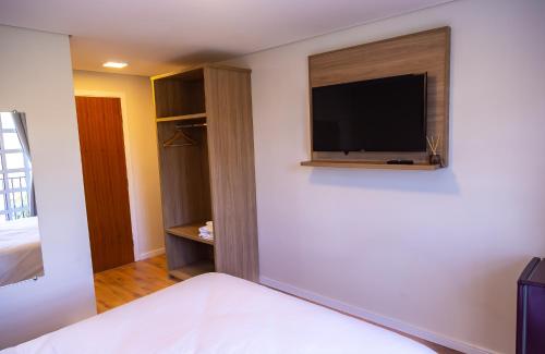 a bedroom with a flat screen tv on a wall at Village de Charme - 2km do Capivari in Campos do Jordão