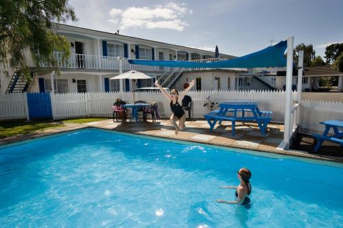 two women are playing in a swimming pool at Boundary Court Motor Inn in Hamilton