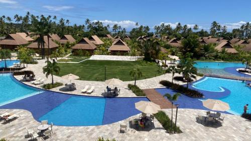 uma vista aérea de uma piscina de resort com guarda-sóis em Apartamento família com 3 quartos no Eco Resort Carneiros em Tamandaré