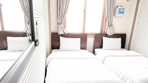two beds in a room with windows at Golden Park Hotel in Jeju