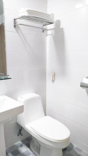 a white bathroom with a toilet and a sink at Golden Park Hotel in Jeju