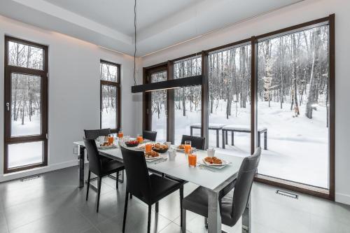 comedor con mesa, sillas y ventanas en Nordic Lodge Tremblant -5 Bdrs,hot Tub,pool Table, en La Conception