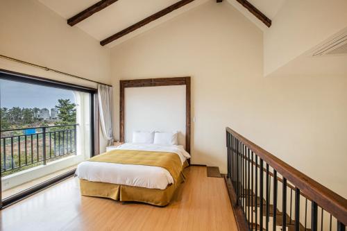 a bedroom with a bed and a large window at Olle Resort in Jeju