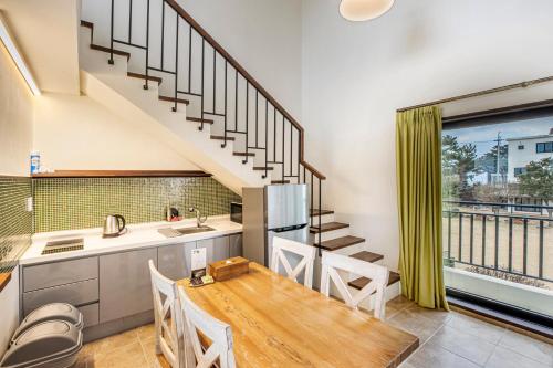 a kitchen and dining room with a table and a staircase at Olle Resort in Jeju