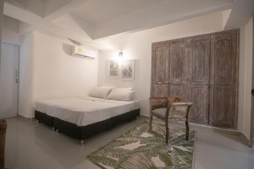 um quarto com uma cama e uma cadeira em Gastelbondo Centro Histórico Plaza Santo Domingo em Cartagena das Índias