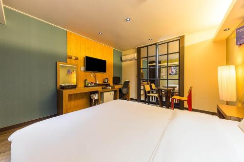 a bedroom with a large bed and a desk with a television at Manhatan Hotel 청주 in Cheongju