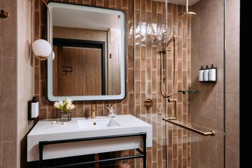 a bathroom with a sink and a mirror and a shower at Mercure Melbourne Doncaster in Doncaster