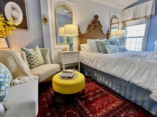 a bedroom with a bed and a chair and a table at Charlotte's Rose Inn in Charlottetown