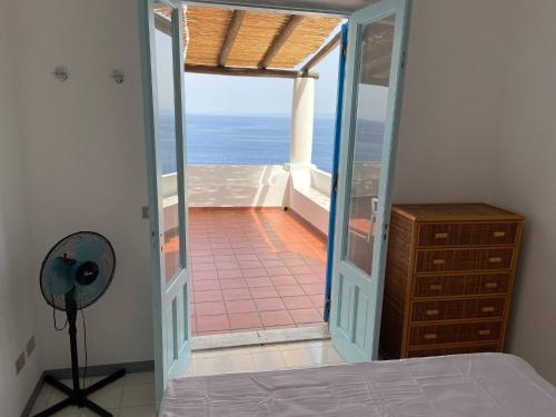 sypialnia z drzwiami prowadzącymi na balkon z widokiem na ocean w obiekcie House sole - Unique Panorama w mieście Lipari