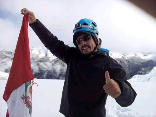 a man giving a thumbs up while holding a flag at Monkeywasi Climbing Hostel in Huaraz