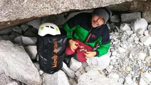 a man sitting on rocks with a helmet in a bag at Monkeywasi Climbing Hostel in Huaraz