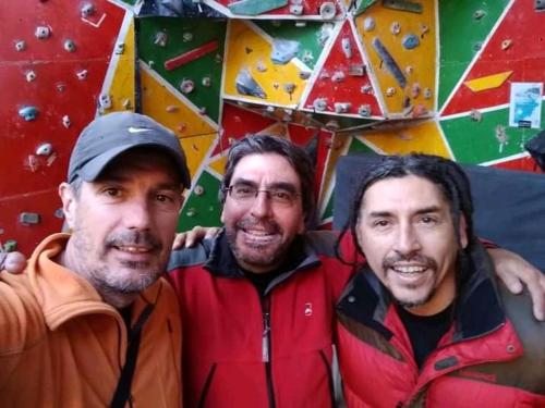 three men standing in front of a climbing wall at Monkeywasi Climbing Hostel in Huaraz