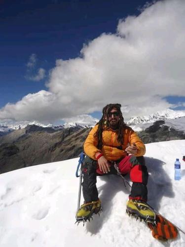 a man sitting on top of a snow covered mountain at Monkeywasi Climbing Hostel in Huaraz