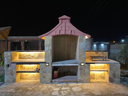 un horno de piedra con techo rojo en un patio por la noche en استراحة ريف حتا en Hatta