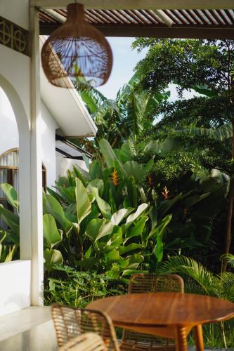 a patio with a wooden table and chairs and plants at Suku Lifestyle Hotel & Villas in Selong Belanak