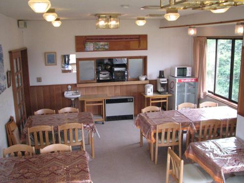 comedor con mesas y sillas y cocina en White Rabbit Madarao, en Iiyama