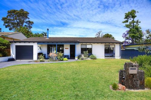 a house with a lawn in front of it at Aloha - Short Drive to Berry & The Beach - Fireplace and Firepit in Shoalhaven Heads
