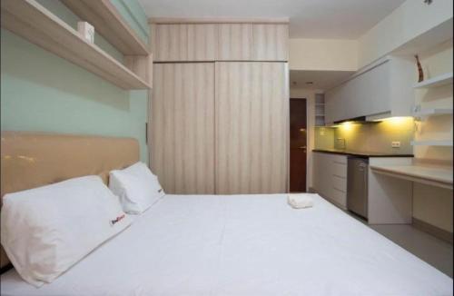 a bedroom with a large white bed in a kitchen at Apartemen Taman Melati Margonda by Winroom in Kukusan