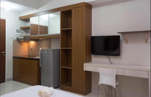 a kitchen with a desk with a television and a counter at Apartemen Taman Melati Margonda by Winroom in Kukusan
