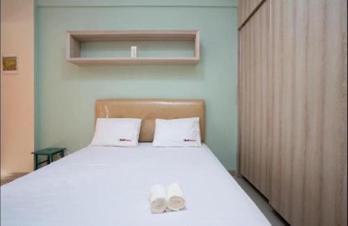 a bedroom with a bed with two slippers on it at Apartemen Taman Melati Margonda by Winroom in Kukusan