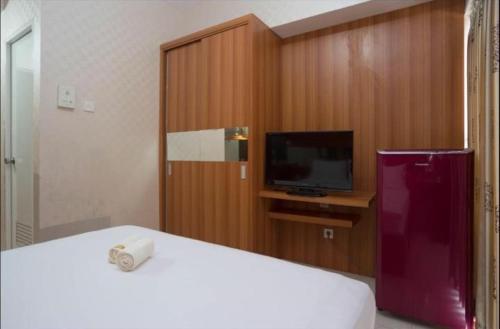 a bedroom with a tv and a bed with a white bed sidx sidx sidx sidx at Apartemen Taman Melati Margonda by Winroom in Kukusan