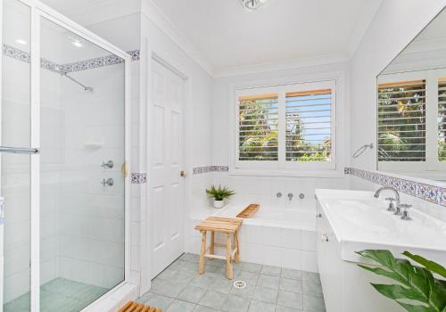 a white bathroom with a shower and a sink at Beach Haven in Shoalhaven Heads