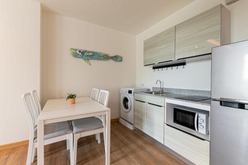 a kitchen with a table and a sink and a refrigerator at Aristo 2 Phuket by RESAVA in Surin Beach
