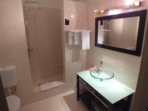 a bathroom with a sink and a shower with a mirror at Hotel Olympic in Port Vila