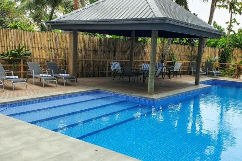 een zwembad met een prieel en een tafel en stoelen bij Seafront Apartment Coral Coast in Korotogo