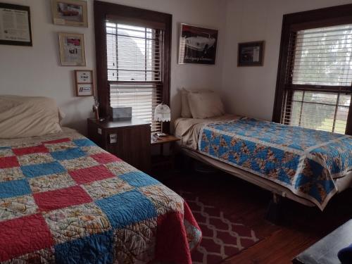 a bedroom with two beds and two windows and a quilt at The Avanti Houses in South Bend
