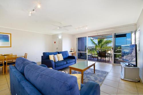 a living room with a blue couch and a table at Bali Hai Apartments Noosa in Noosa Heads