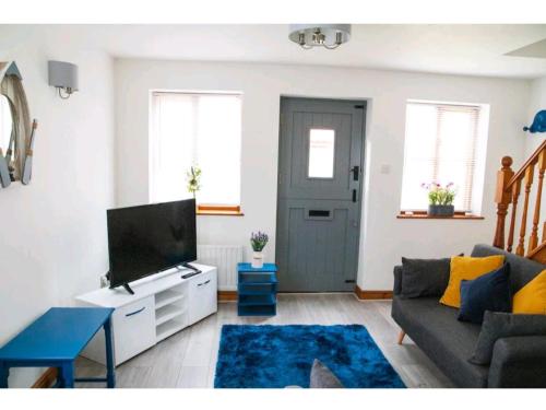 a living room with a couch and a tv at Pebble Cottage, Cromer in Cromer
