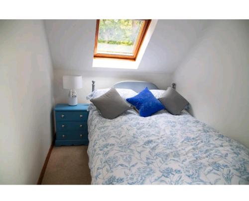 a bedroom with a bed with pillows and a window at Pebble Cottage, Cromer in Cromer