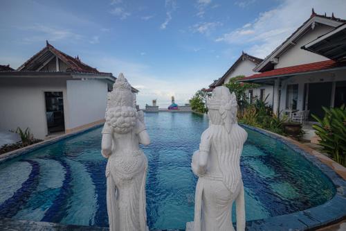 two statues standing in front of a swimming pool at Salt Resort & Spa in Amed