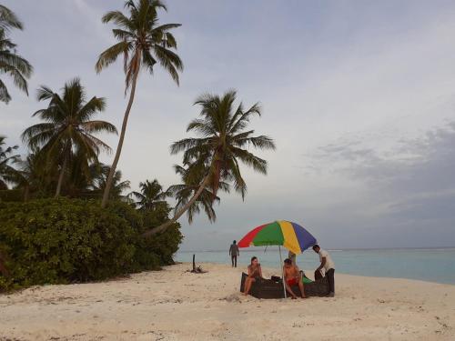 a group of people sitting under an umbrella on a beach at Island Life Maldives Retreat & Spa in Magoodhoo