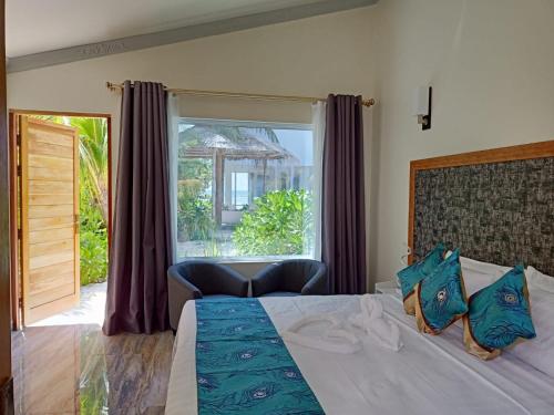 sypialnia z łóżkiem i dużym oknem w obiekcie Island Life Maldives Retreat & Spa w mieście Magoodhoo