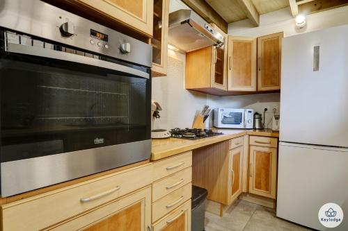 a kitchen with wooden cabinets and a stainless steel appliance at T2 - Le Reflet d'O 3 étoiles - 50 m2 - Saint Gilles Les Bains in Filaos