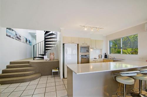 a kitchen with a white refrigerator and a staircase at Bali Hai Apartments Noosa in Noosa Heads