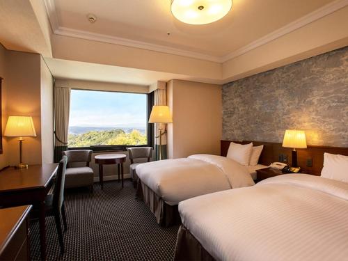 a hotel room with two beds and a window at SHIROYAMA HOTEL kagoshima in Kagoshima