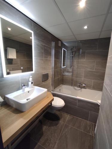 a bathroom with a sink and a tub and a toilet at Akzent City-Hotel Kleve in Kleve