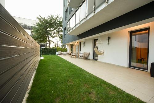 a backyard of a building with a grass yard at VACATION FEEL - 2BR Apartment with Terrace & Private Parking in Baneasa in Bucharest