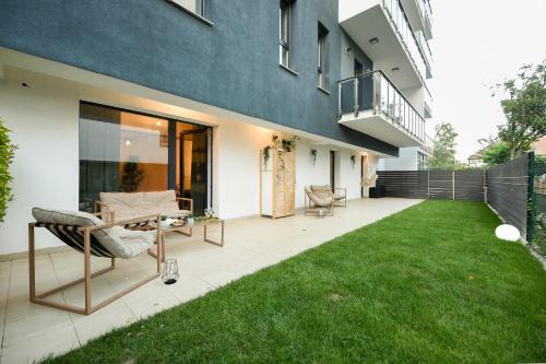 a patio with green grass in front of a house at VACATION FEEL - 2BR Apartment with Terrace & Private Parking in Baneasa in Bucharest