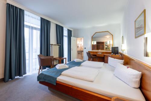 a hotel room with a bed and a desk and a mirror at Trip Inn Klee am Park Wiesbaden in Wiesbaden