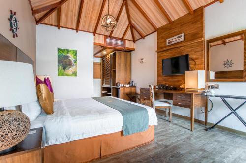 a bedroom with a bed and a desk and a television at Plumeria Maldives in Thinadhoo