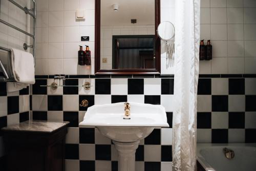 a black and white bathroom with a sink and a mirror at Clarion Hotel Wisby in Visby