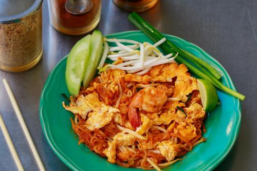 a green plate of food with shrimp and vegetables at Sleepbox Hostel Suratthani in Suratthani