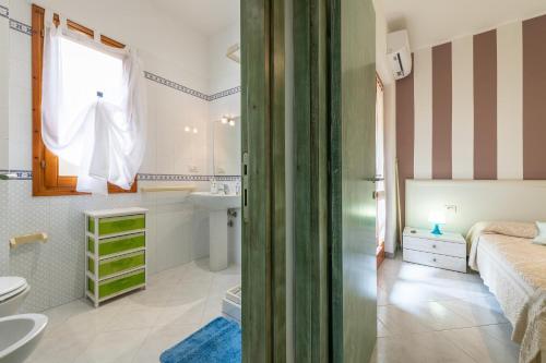una camera da letto con un letto e un bagno con un lavandino di Bilocale con Piscina a Villasimius a Villasimius