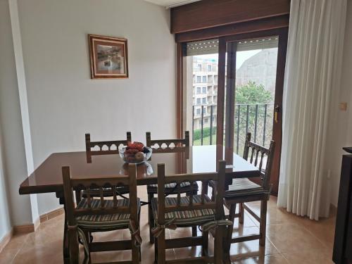 comedor con mesa y sillas y balcón en Apartamento VOLVERÁS, en Sanxenxo