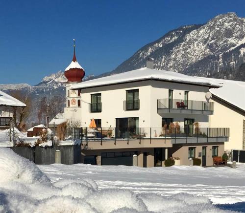 ein großes weißes Gebäude mit Balkon im Schnee in der Unterkunft Haus Klinger in Vandans